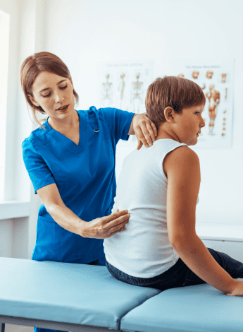 A boy having his spine checked by a health professional